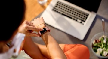 Person sitting in front of a laptop and phone, looking tired and overwhelmed, symbolizing the impact of constant screen time on mental health and wellbeing.
