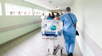 A young nurse in uniform confidently assisting an elderly patient in a hospital room, symbolizing the transition from nursing student to professional caregiver.
