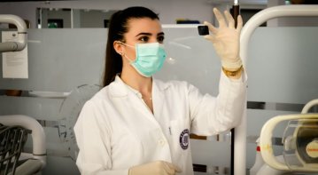 A confident nurse in professional scrubs attentively listens to an elderly patient in a hospital room, illustrating how strong foundational training helps nurses build trust and rapport quickly.