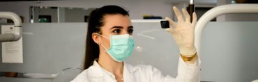A confident nurse in professional scrubs attentively listens to an elderly patient in a hospital room, illustrating how strong foundational training helps nurses build trust and rapport quickly.