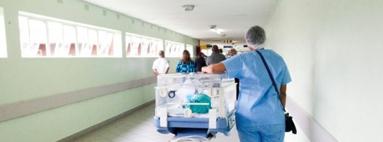 A young nurse in uniform confidently assisting an elderly patient in a hospital room, symbolizing the transition from nursing student to professional caregiver.