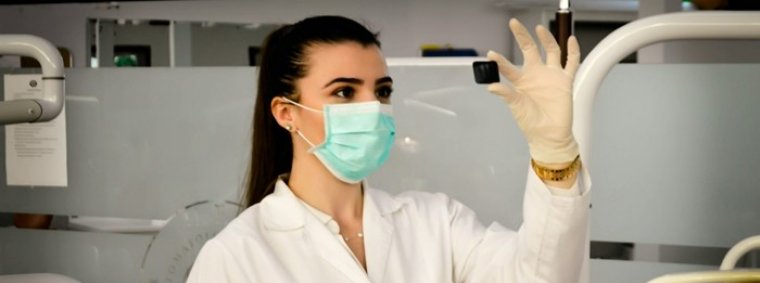 A confident nurse in professional scrubs attentively listens to an elderly patient in a hospital room, illustrating how strong foundational training helps nurses build trust and rapport quickly.